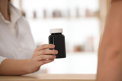Photo of Pharmacist giving medicine to customer in drugstore, closeup