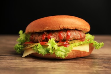 One tasty burger with patty, lettuce and cheese on wooden table, closeup