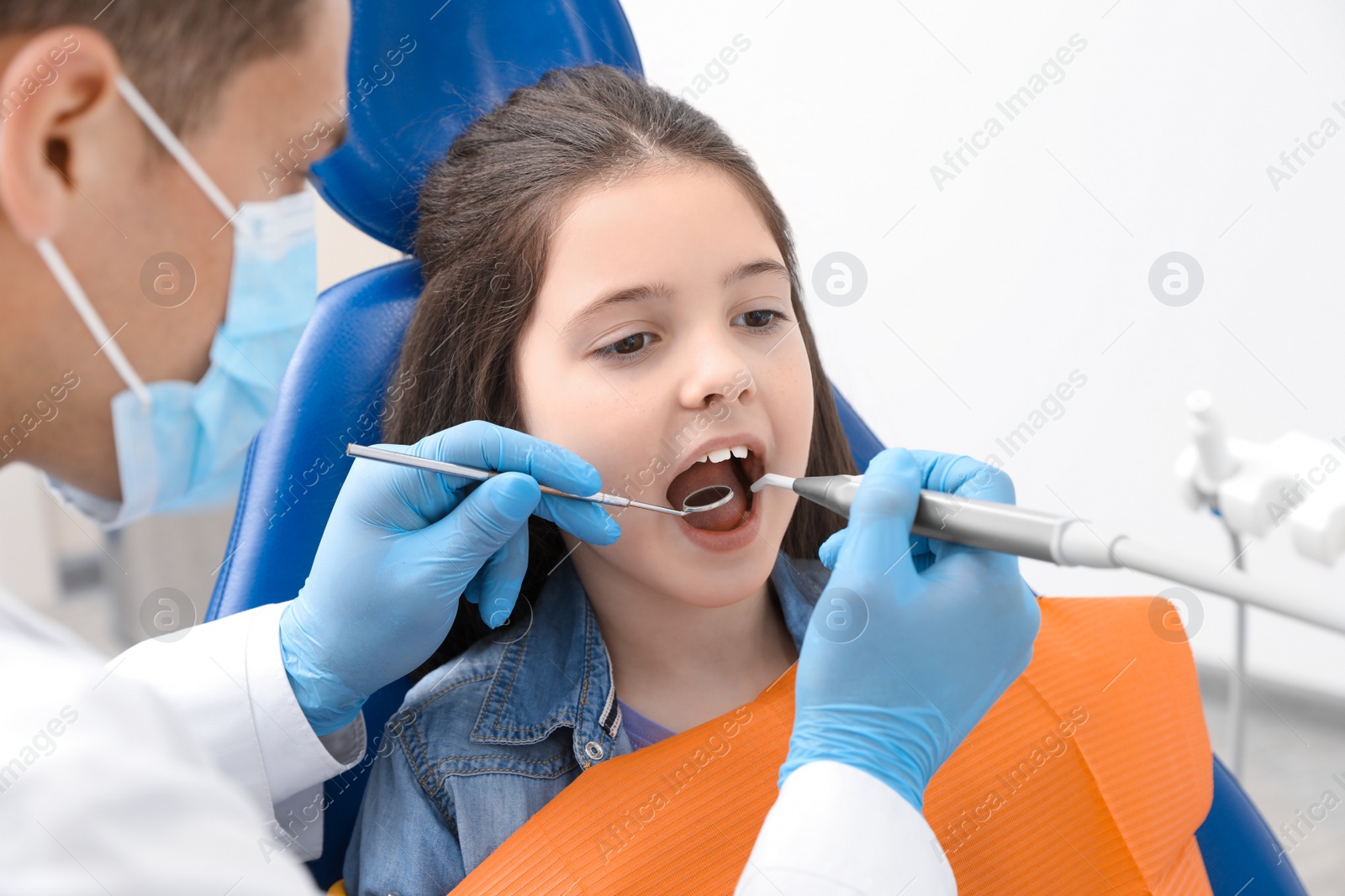 Photo of Professional dentist working with little girl in clinic