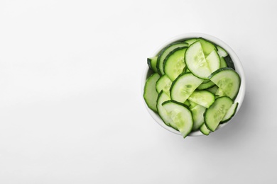 Photo of Bowl with slices of ripe cucumber on white background, top view