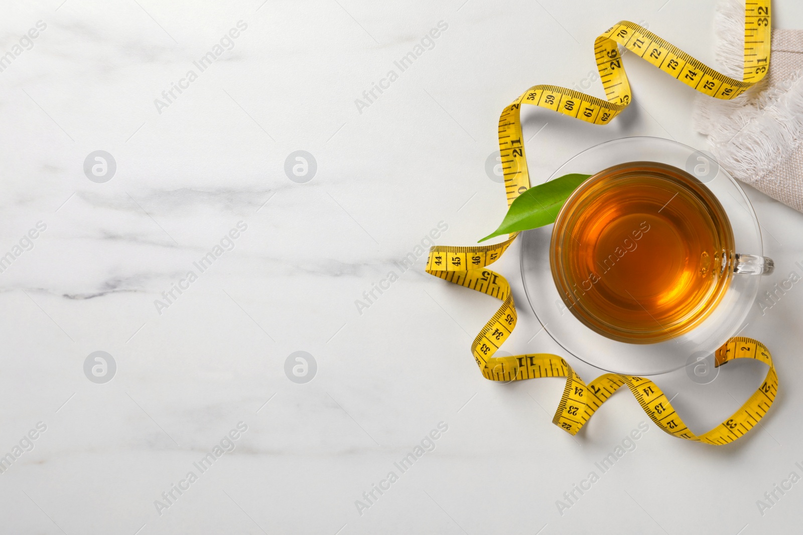 Photo of Flat lay composition with herbal diet tea and measuring tape on white marble table, space for text. Weight loss concept