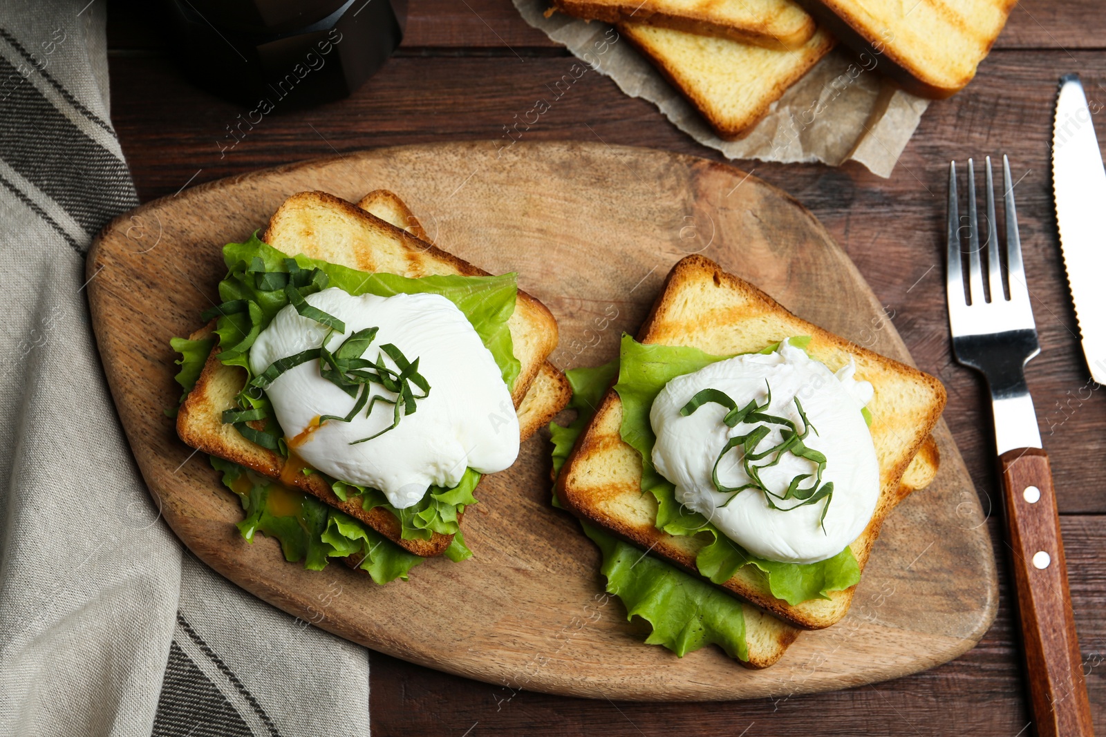 Photo of Delicious poached egg sandwiches served on wooden table, flat lay