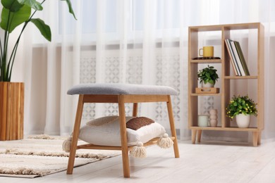 Photo of Spring atmosphere. Wooden bench with pillow, houseplant and shelving unit in stylish room