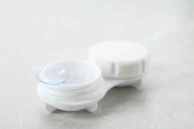 Photo of Case with contact lens on light grey table, closeup
