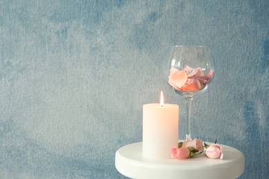 Candle with floral decor on table against color background