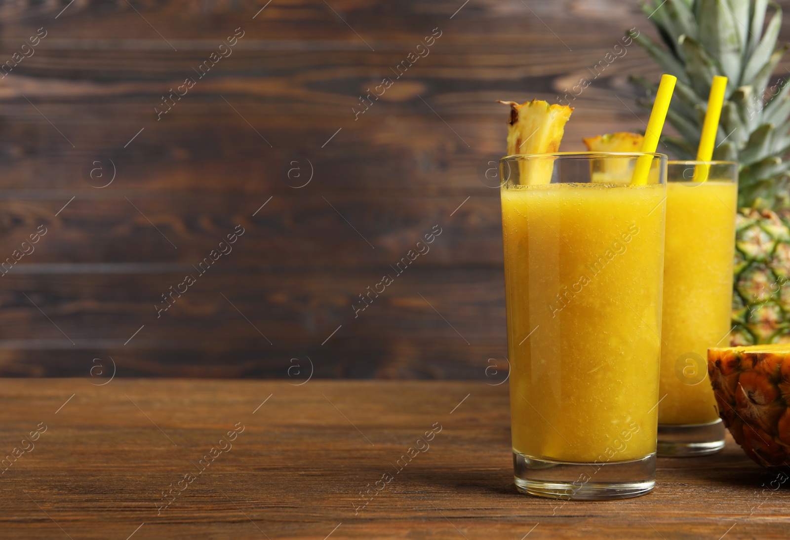 Photo of Tasty pineapple smoothie on wooden table, space for text