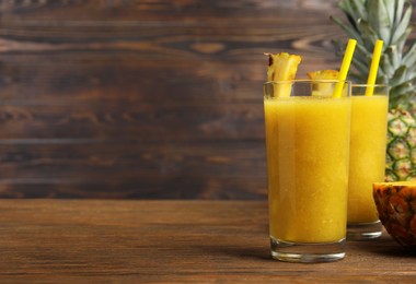 Photo of Tasty pineapple smoothie on wooden table, space for text