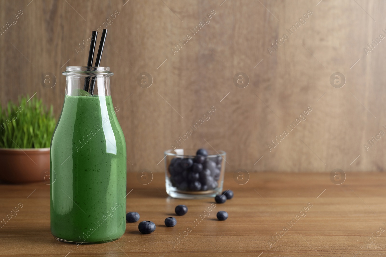 Photo of Bottle of spirulina smoothie with berries on table. Space for text