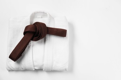 Photo of Brown karate belt and kimono on white background, top view. Space for text