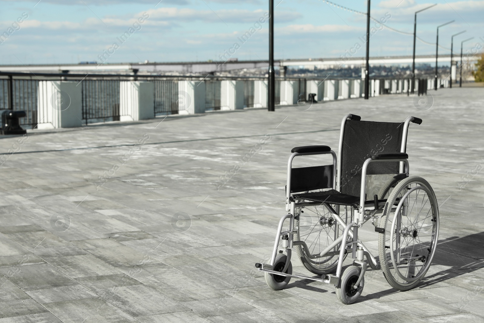 Photo of Empty wheelchair outdoors on sunny day. Space for text