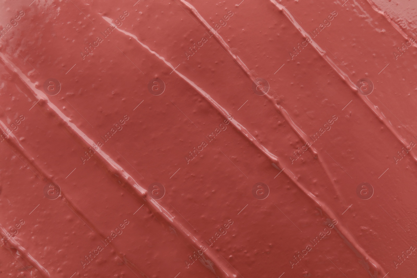 Photo of Coral liquid lipstick smudged as background, top view