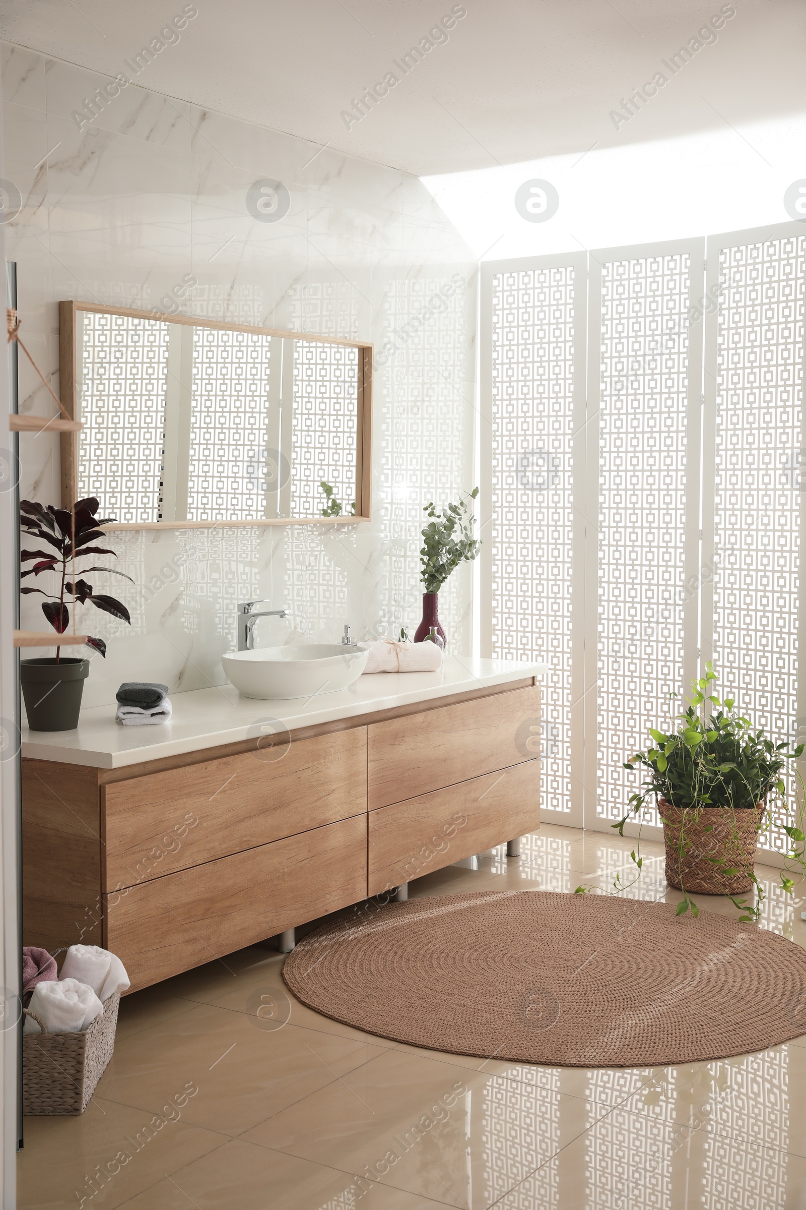 Photo of Stylish bathroom interior with countertop, mirror and plants. Design idea