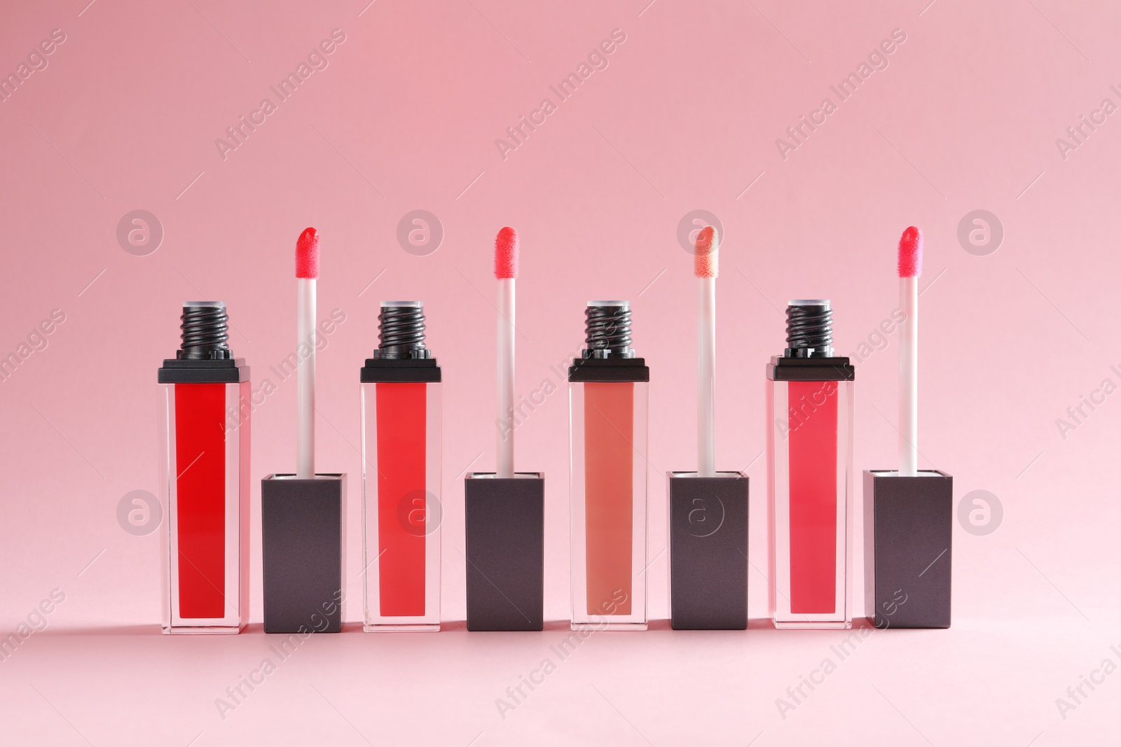 Photo of Liquid lipsticks with applicators on color background