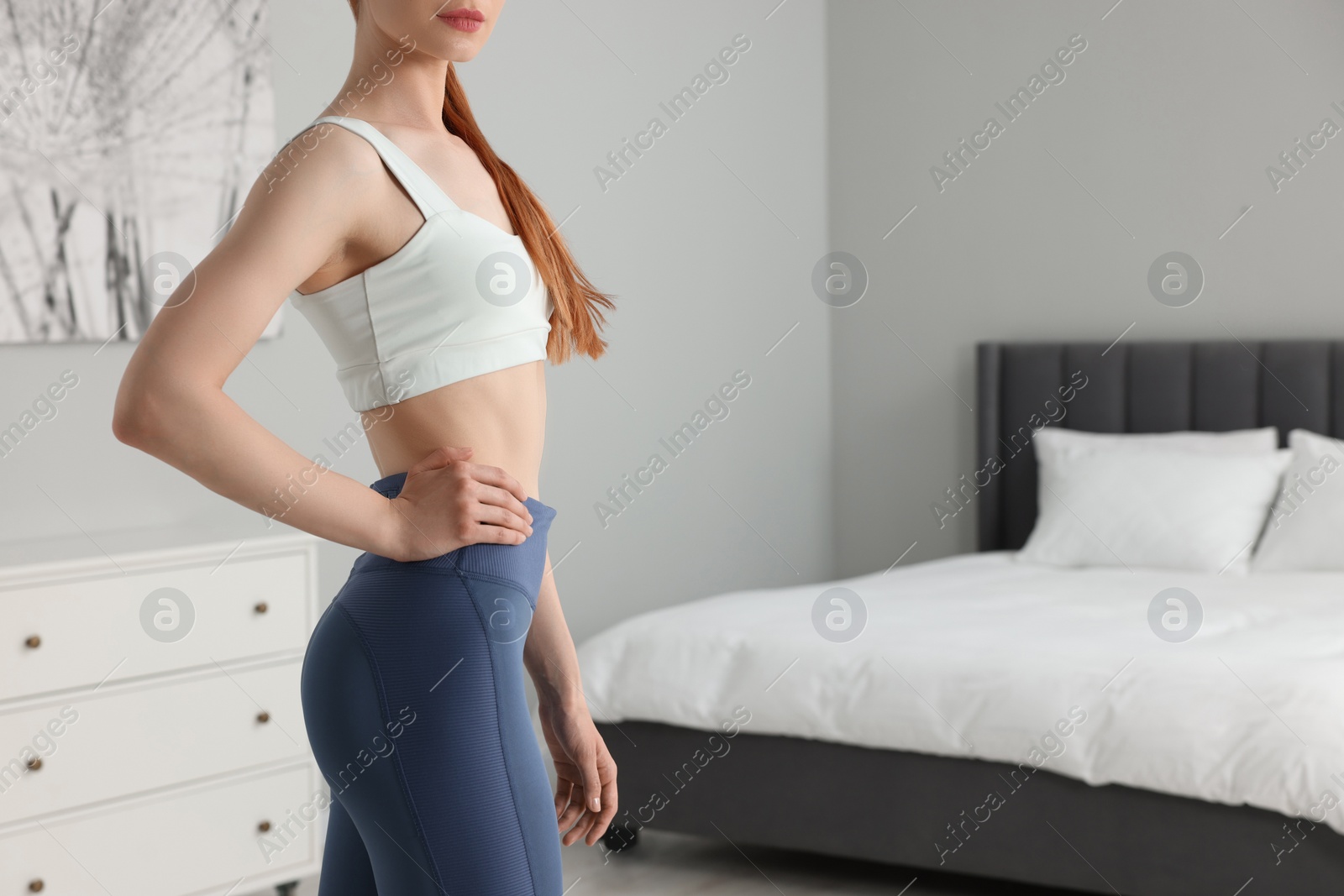 Photo of Woman wearing sportswear in bedroom, closeup. Space for text