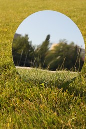 Photo of Round mirror on grass reflecting trees and sky