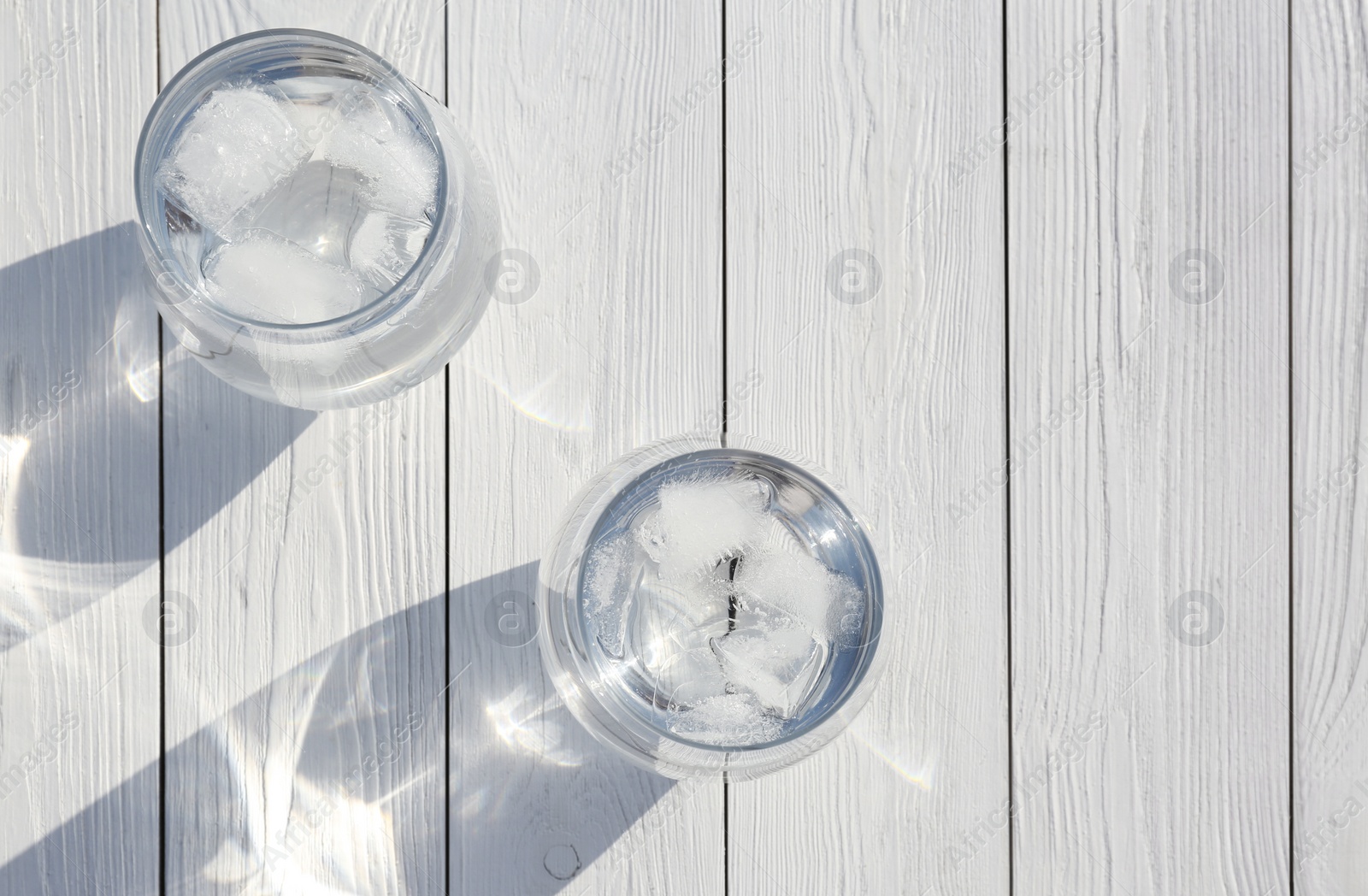Photo of Glasses of refreshing drink with ice for hot summer day on wooden table, top view. Space for text