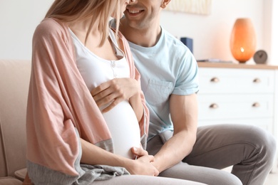 Photo of Young pregnant woman with her husband at home