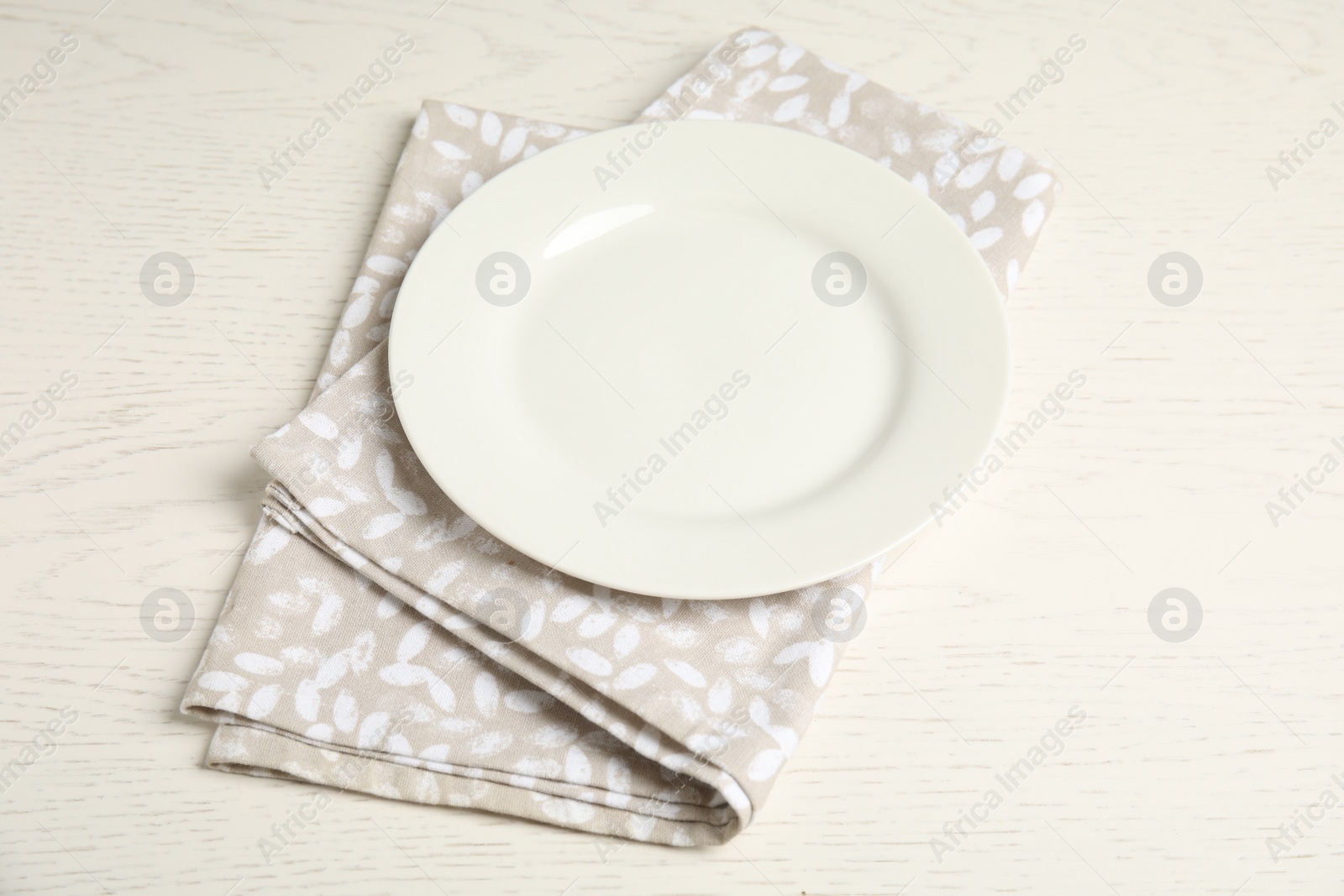 Photo of Empty plate and napkin on white wooden table