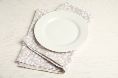 Photo of Empty plate and napkin on white wooden table