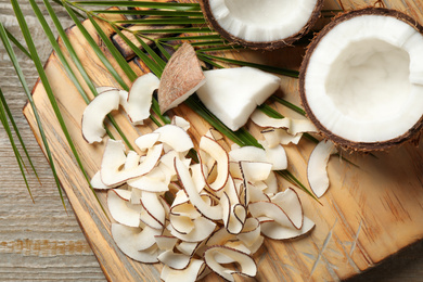 Photo of Composition with tasty coconut chips on wooden table, above view