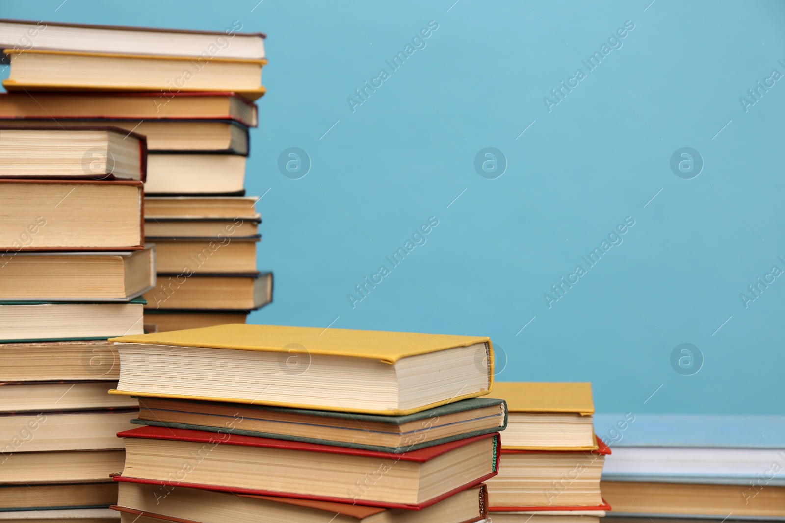 Photo of Many hardcover books on turquoise background, space for text. Library material