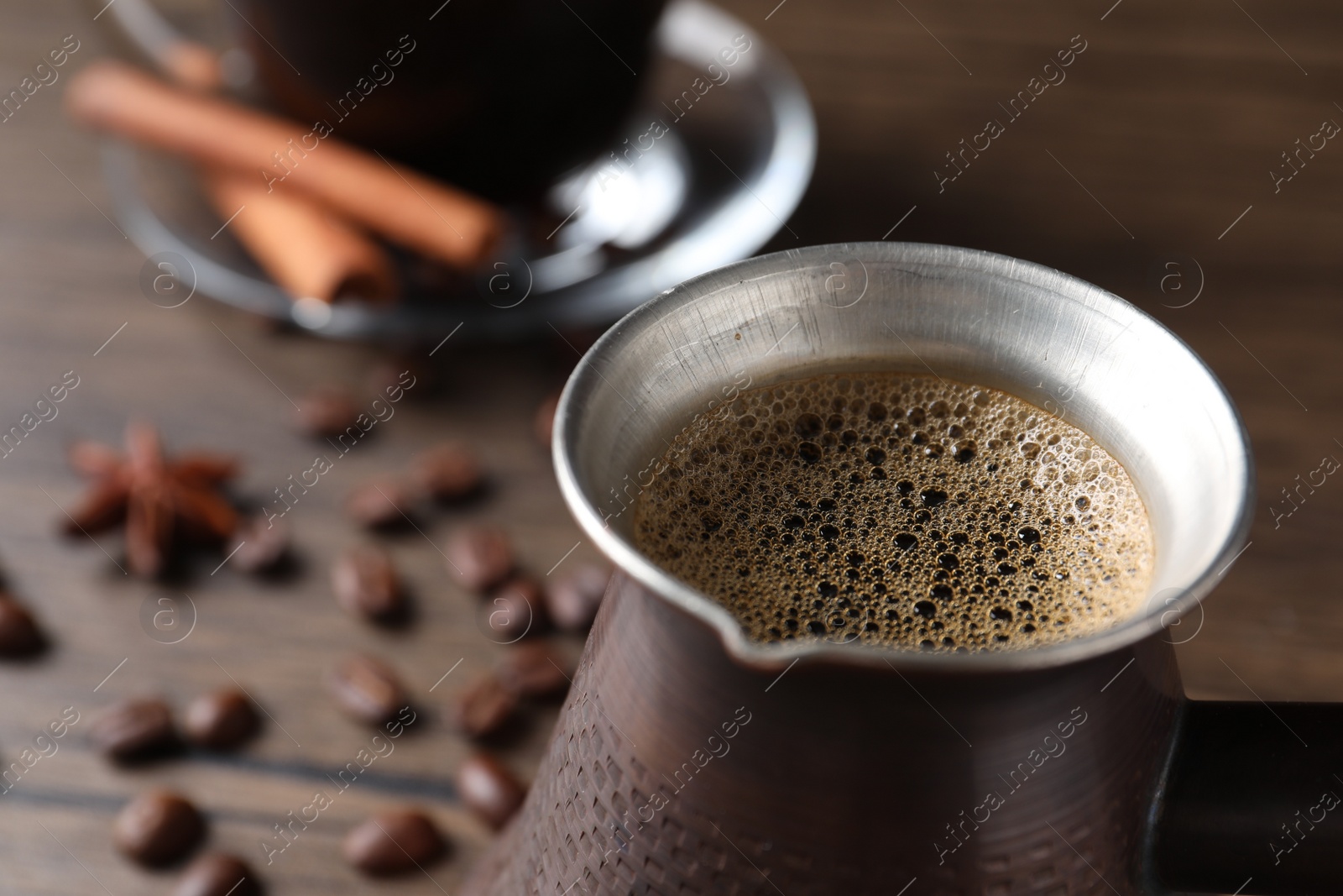 Photo of Turkish coffee in cezve on wooden table, closeup. Space for text