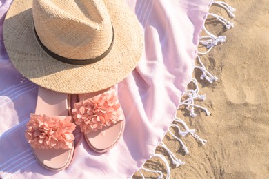 Photo of Blanket with stylish slippers and straw hat on sandy beach, above view. Space for text