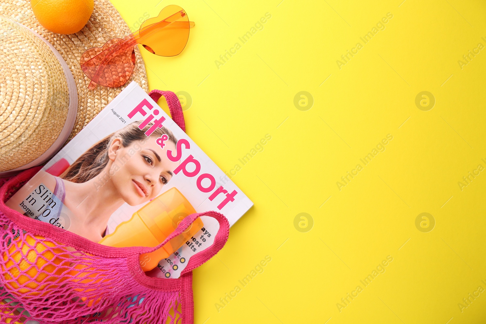 Photo of String bag with fresh oranges, magazine and beach accessories on yellow background, flat lay. Space for text