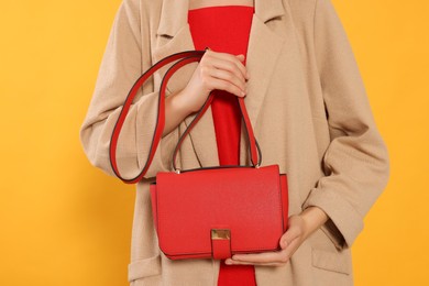 Woman with stylish bag on yellow background, closeup