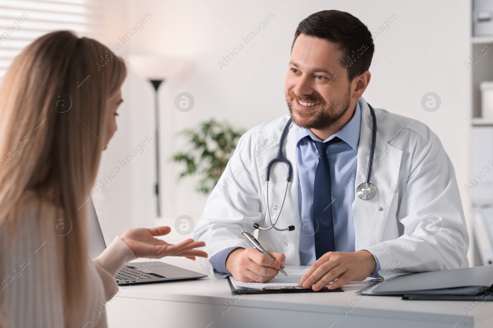 Photo of Professional doctor working with patient at white table in hospital