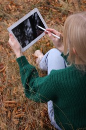Young woman drawing on tablet outdoors, above view