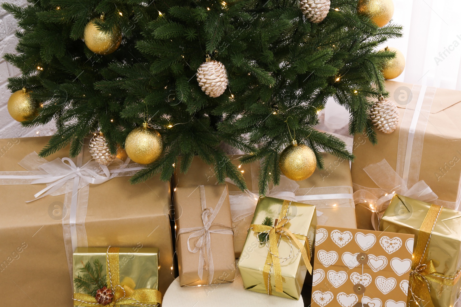 Photo of Pile of gift boxes near Christmas tree indoors