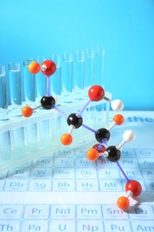 Photo of Molecular model and test tubes on periodic table against light blue background