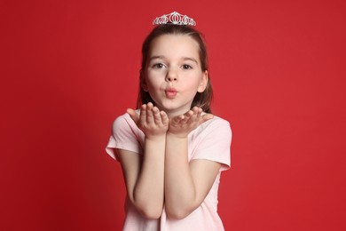 Cute girl in diadem on red background. Little princess
