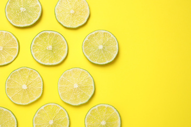 Photo of Fresh juicy lime slices on yellow background, flat lay. Space for text