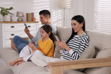 Photo of Internet addiction. Family with gadgets on sofa in living room