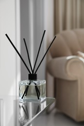 Photo of Aromatic reed air freshener on table indoors, space for text