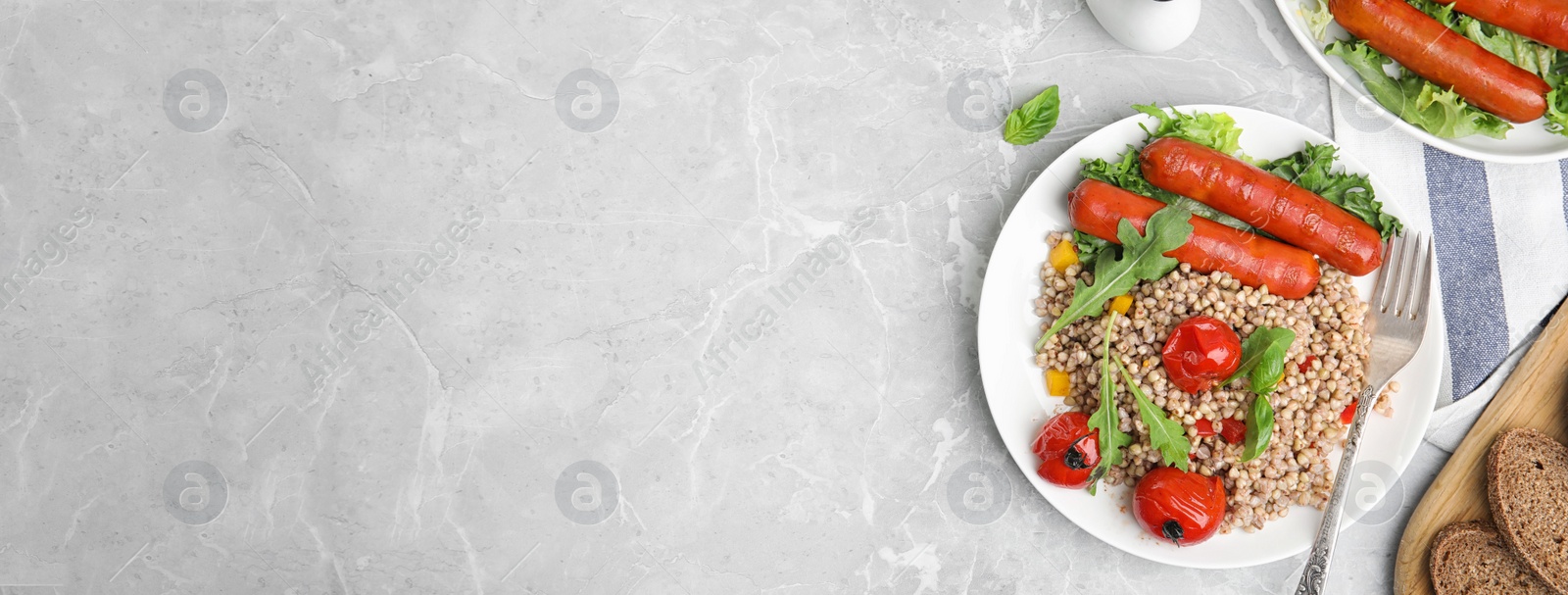 Image of Tasty buckwheat porridge and sausages on light grey marble table, flat lay with space for text. Banner design