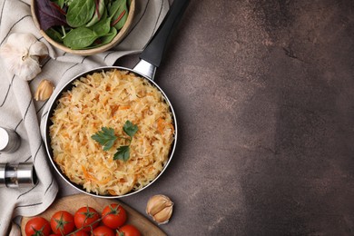 Frying pan with sauerkraut and products on brown table, flat lay. Space for text