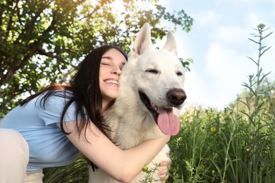 Photo of Teenage girl hugging her white Swiss Shepherd dog in park