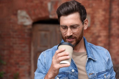 Handsome bearded man with paper cup outdoors. Space for text