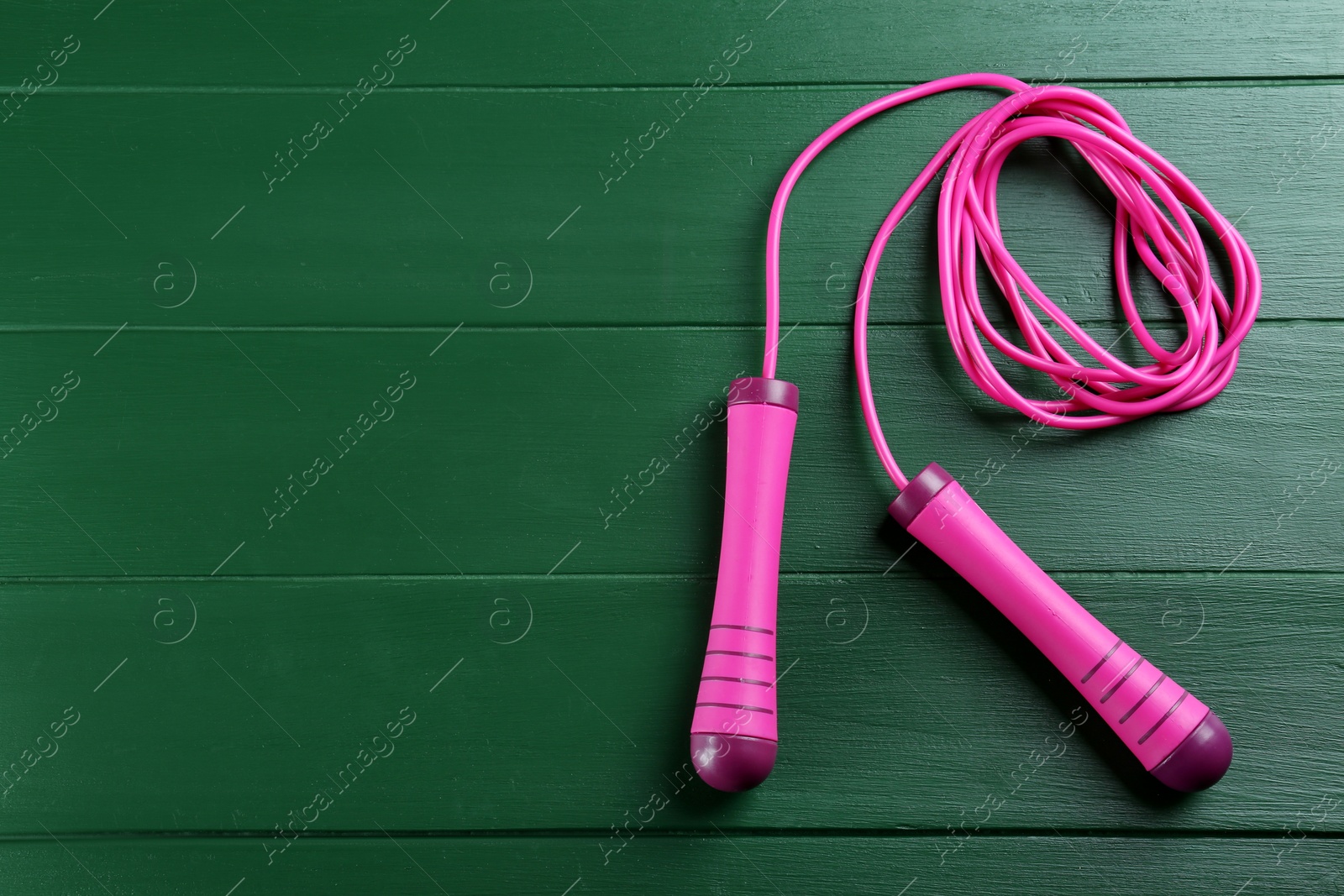 Photo of Skipping rope on green wooden table, top view. Space for text