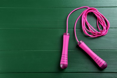 Skipping rope on green wooden table, top view. Space for text