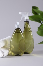 Photo of Bottles of cleaning product and rolled rags on light background