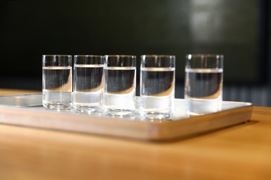 Photo of Shots of vodka on bar counter against dark background
