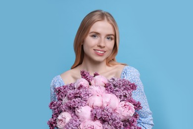 Beautiful woman with bouquet of spring flowers on light blue background