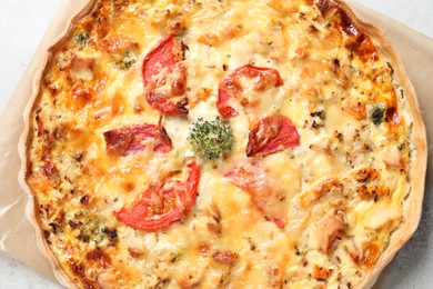 Photo of Tasty quiche with cheese and tomatoes on light grey table, top view