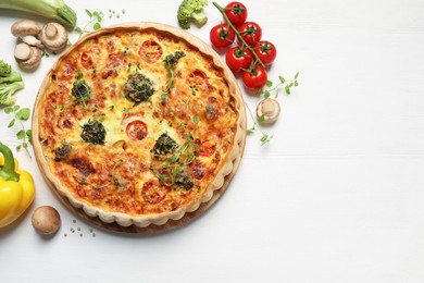 Delicious homemade vegetable quiche and ingredients on wooden table, flat lay. Space for text