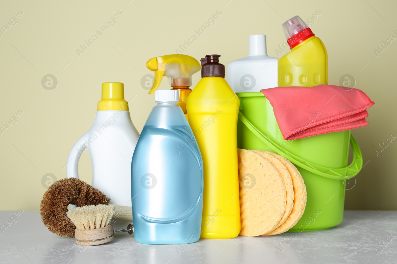 Photo of Different cleaning supplies and tools on table against beige