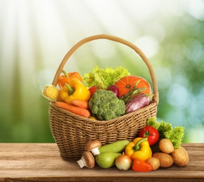 Wicker basket with fresh vegetables on wooden table against blurred background